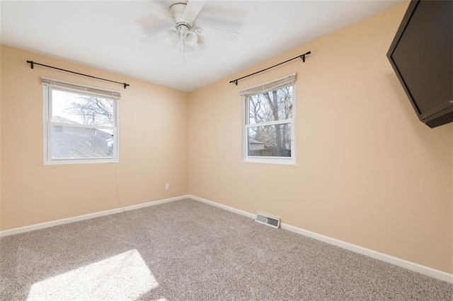 carpeted spare room featuring a ceiling fan, baseboards, and visible vents