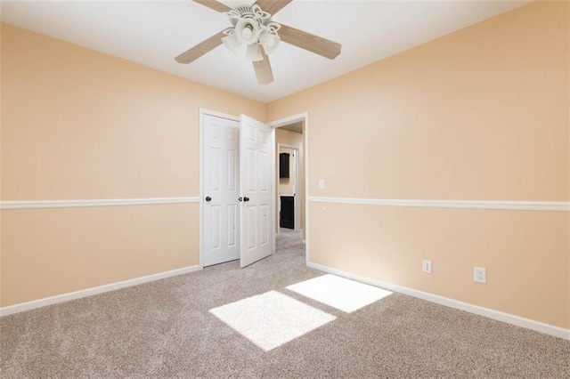 carpeted spare room featuring a ceiling fan and baseboards