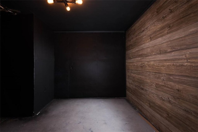 spare room featuring concrete flooring and wood walls