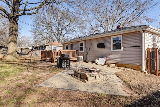 rear view of house featuring fence, a fire pit, a wooden deck, a chimney, and a patio area