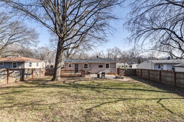 back of house with a fenced backyard, a lawn, a fire pit, and a deck