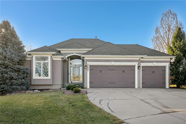 view of front of home with stucco siding, a front lawn, driveway, roof with shingles, and an attached garage