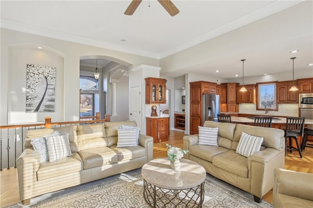 living room featuring decorative columns, arched walkways, a ceiling fan, and crown molding