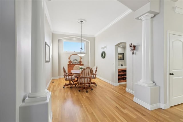 dining room featuring decorative columns, light wood-style floors, and ornamental molding