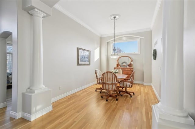 dining area with decorative columns, baseboards, light wood-style flooring, and ornamental molding