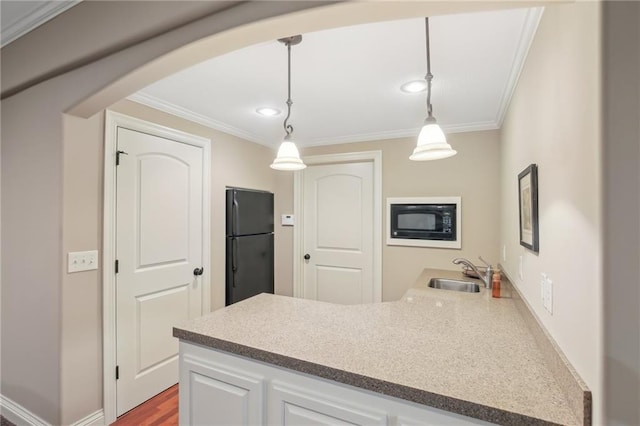 kitchen featuring arched walkways, black appliances, crown molding, and a sink