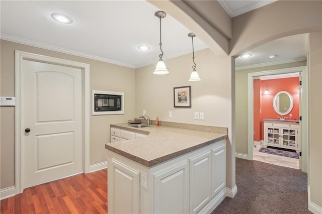 kitchen featuring a peninsula, white cabinets, arched walkways, and a sink