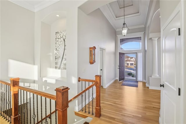 foyer entrance with decorative columns, baseboards, wood finished floors, and ornamental molding