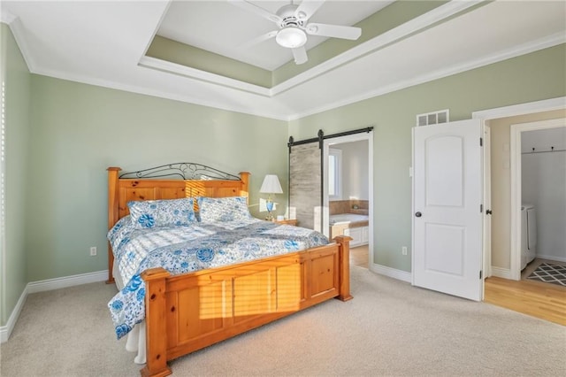 bedroom with baseboards, visible vents, a barn door, light carpet, and a raised ceiling