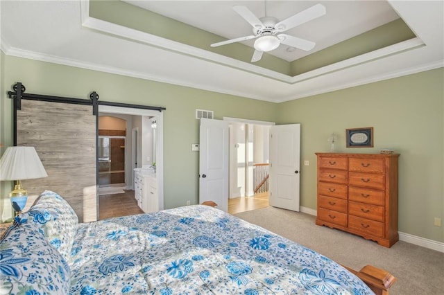 carpeted bedroom featuring a ceiling fan, baseboards, visible vents, a tray ceiling, and a barn door