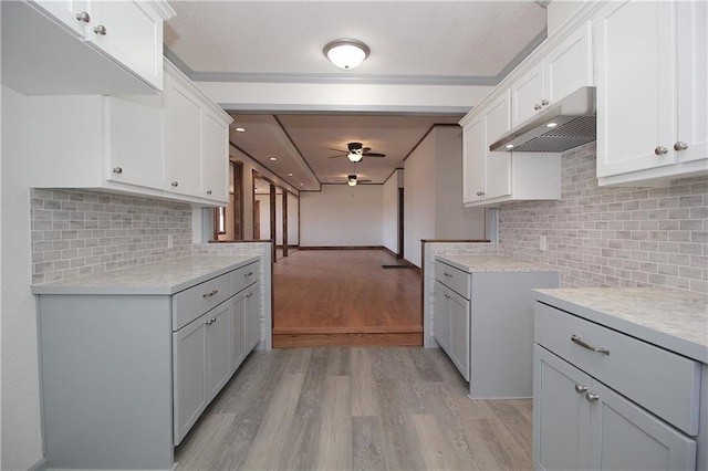 kitchen featuring light countertops, a ceiling fan, light wood-style floors, and under cabinet range hood