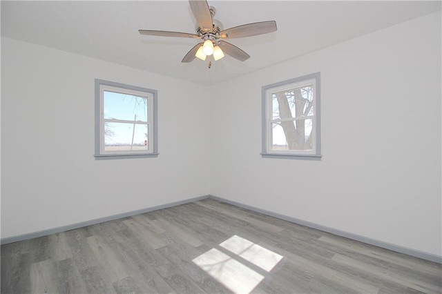 spare room featuring a healthy amount of sunlight, baseboards, and light wood finished floors