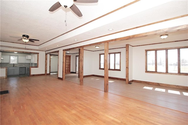 unfurnished living room with a sink, baseboards, a textured ceiling, and wood finished floors