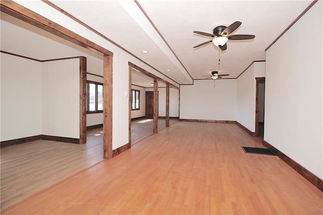 empty room with crown molding, baseboards, visible vents, and light wood finished floors