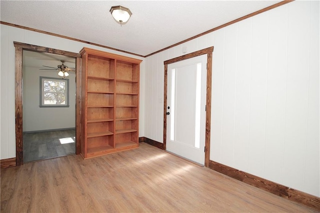 empty room featuring a textured ceiling, wood finished floors, and ornamental molding