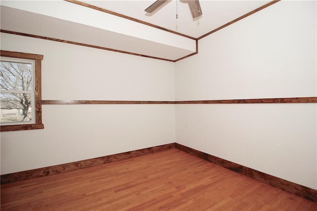 spare room featuring a ceiling fan, crown molding, baseboards, and wood finished floors