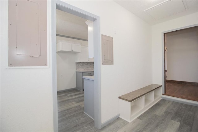 corridor with electric panel, light wood-style floors, and baseboards