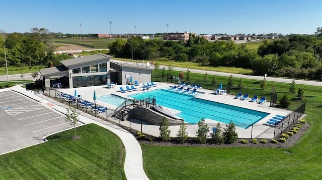 community pool with a yard, a patio, and fence