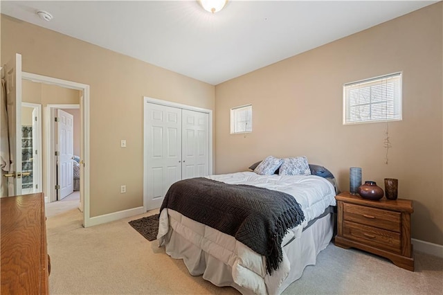 bedroom featuring a closet, baseboards, and light colored carpet