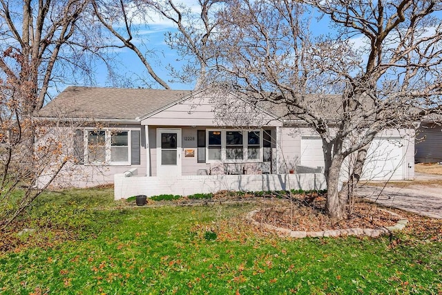 view of front of property with a front lawn, an attached garage, driveway, and roof with shingles