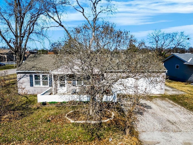 view of front facade with dirt driveway and a shingled roof