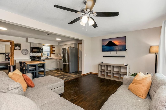 living room with dark wood-type flooring, baseboards, and ceiling fan