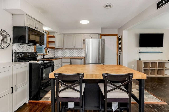 kitchen with black appliances, a sink, open shelves, dark wood-style floors, and decorative backsplash