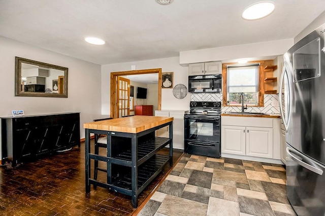 kitchen featuring black appliances, a sink, backsplash, wood finished floors, and white cabinetry