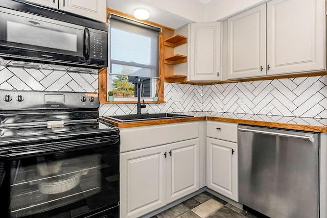 kitchen featuring a sink, black appliances, stone finish floor, white cabinetry, and tasteful backsplash