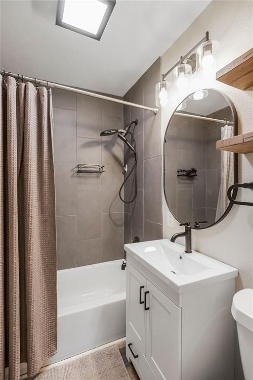 full bath featuring shower / bath combo with shower curtain, toilet, and vanity