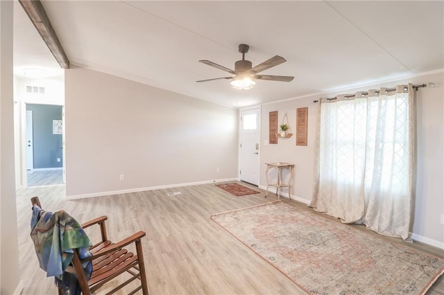 interior space featuring a ceiling fan, visible vents, wood finished floors, baseboards, and ornamental molding