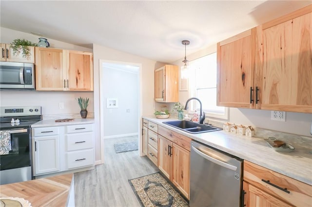 kitchen featuring light brown cabinets, a sink, appliances with stainless steel finishes, light wood finished floors, and light countertops