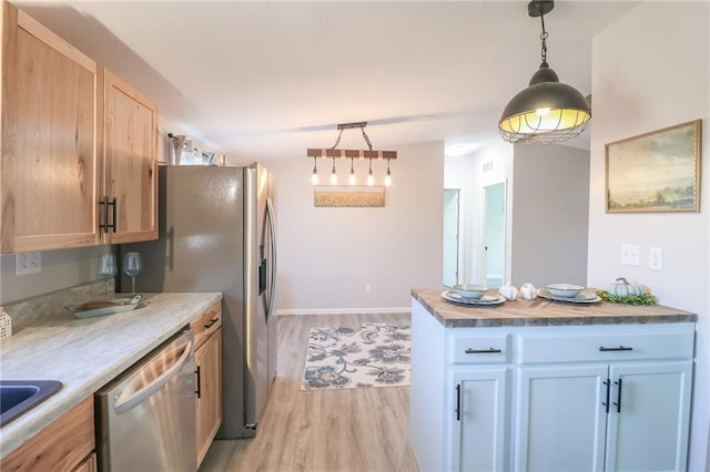 kitchen featuring light wood-style flooring, light countertops, track lighting, pendant lighting, and stainless steel dishwasher