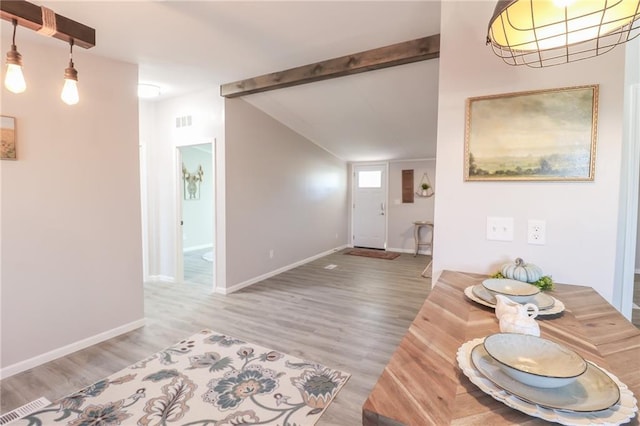 entryway with visible vents, lofted ceiling with beams, baseboards, and wood finished floors