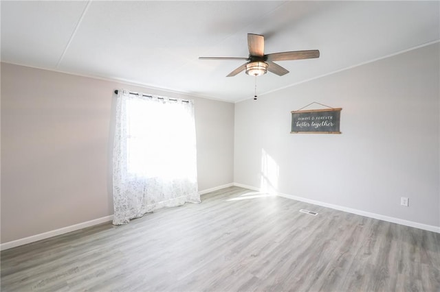 empty room featuring ceiling fan, baseboards, wood finished floors, and ornamental molding