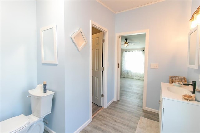 bathroom featuring vanity, toilet, wood finished floors, and baseboards