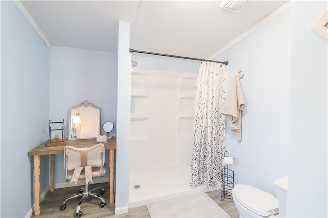 bathroom with toilet, a stall shower, ornamental molding, wood finished floors, and baseboards