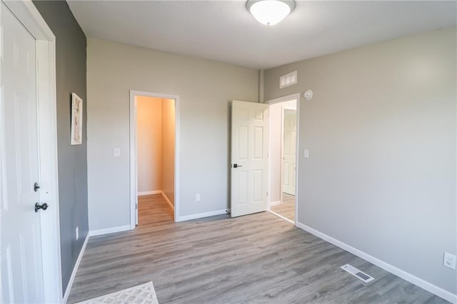 unfurnished bedroom featuring a closet, visible vents, baseboards, and wood finished floors