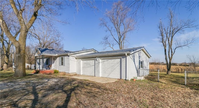 exterior space with a garage, dirt driveway, and fence