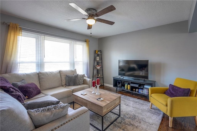 living room featuring a ceiling fan, wood finished floors, baseboards, and a textured ceiling