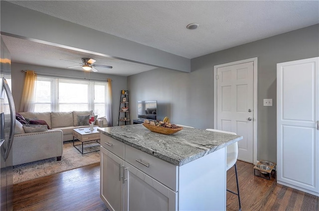 kitchen featuring open floor plan, a kitchen breakfast bar, a center island, and dark wood-type flooring