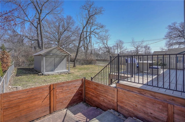 view of yard with an outbuilding, a wooden deck, a storage shed, and a fenced backyard