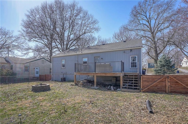 rear view of property with fence, an outdoor fire pit, central AC unit, a deck, and a gate