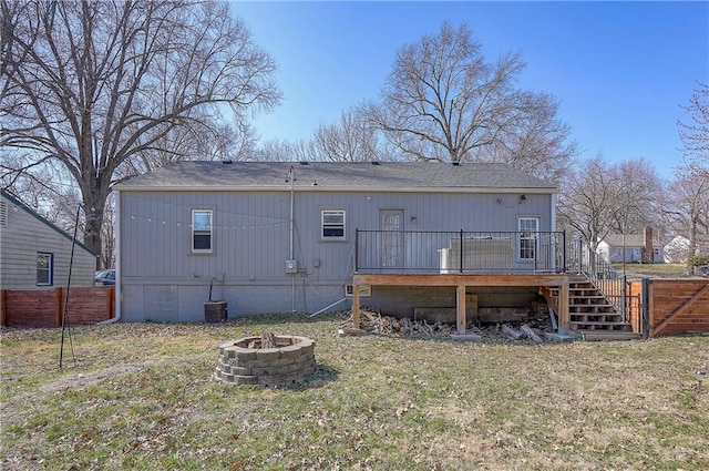 back of property with a yard, fence, a deck, and an outdoor fire pit