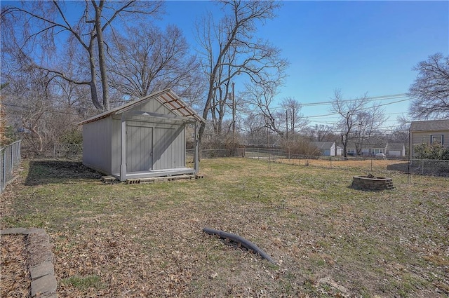 view of yard with an outbuilding, a shed, a fire pit, and a fenced backyard