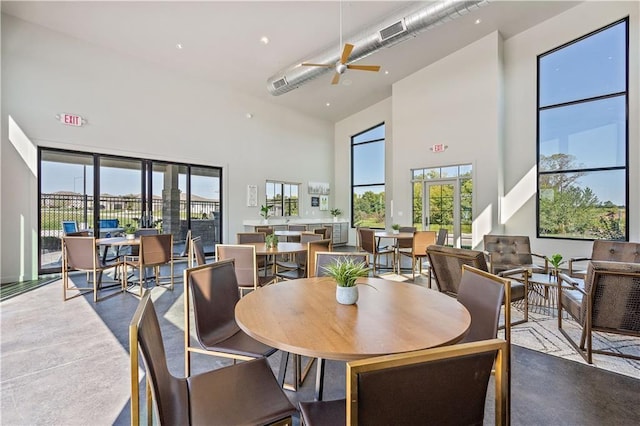 dining area featuring finished concrete floors, visible vents, a towering ceiling, and ceiling fan