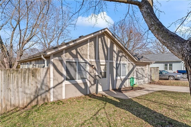 exterior space featuring concrete driveway, fence, and a lawn