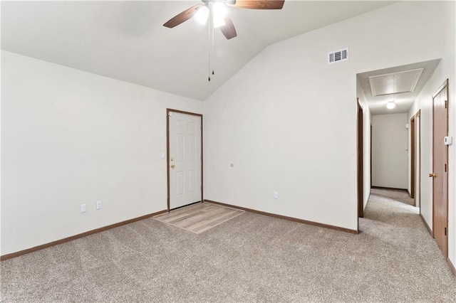 carpeted empty room with baseboards, visible vents, attic access, ceiling fan, and vaulted ceiling