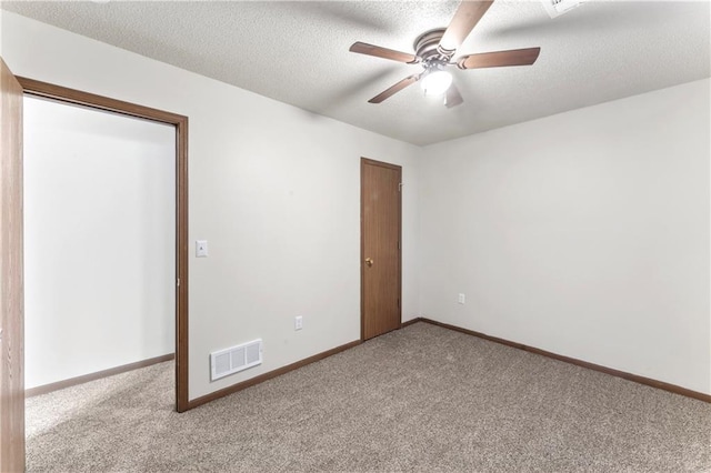 carpeted spare room featuring visible vents, baseboards, a textured ceiling, and a ceiling fan