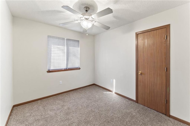 spare room with carpet, baseboards, and a textured ceiling